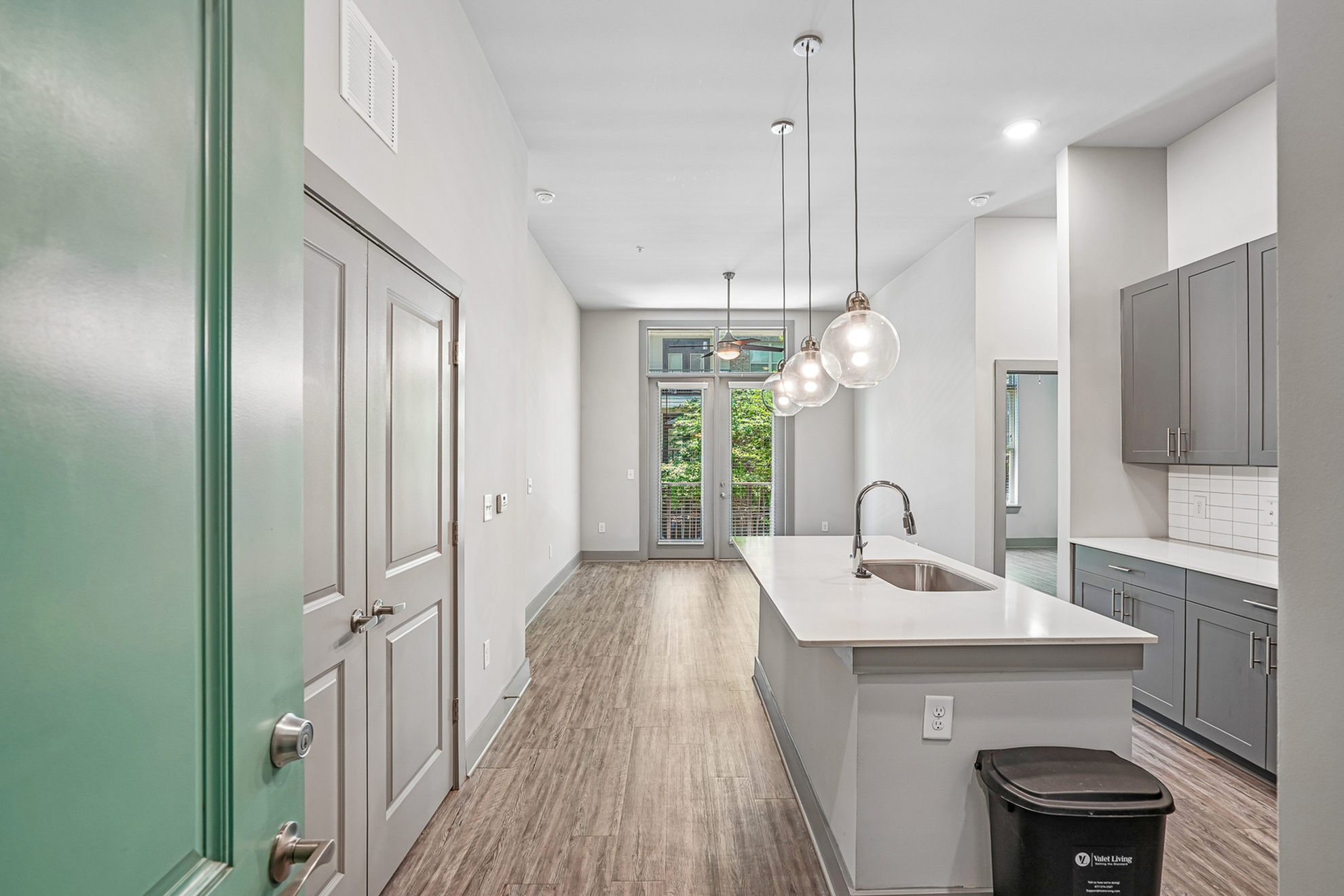 Modern kitchen with sleek countertops, pendant lighting, and a bright, open layout leading to a private balcony.