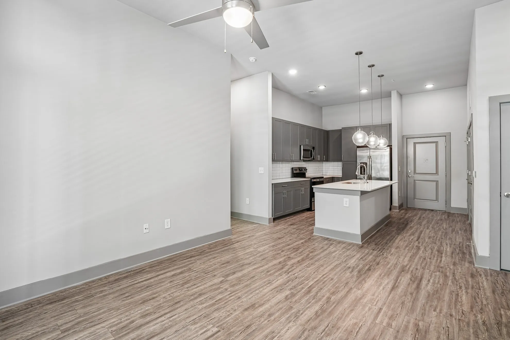 Modern kitchen with sleek gray cabinets, stainless steel appliances, and a stylish island bar in an open-concept apartment.