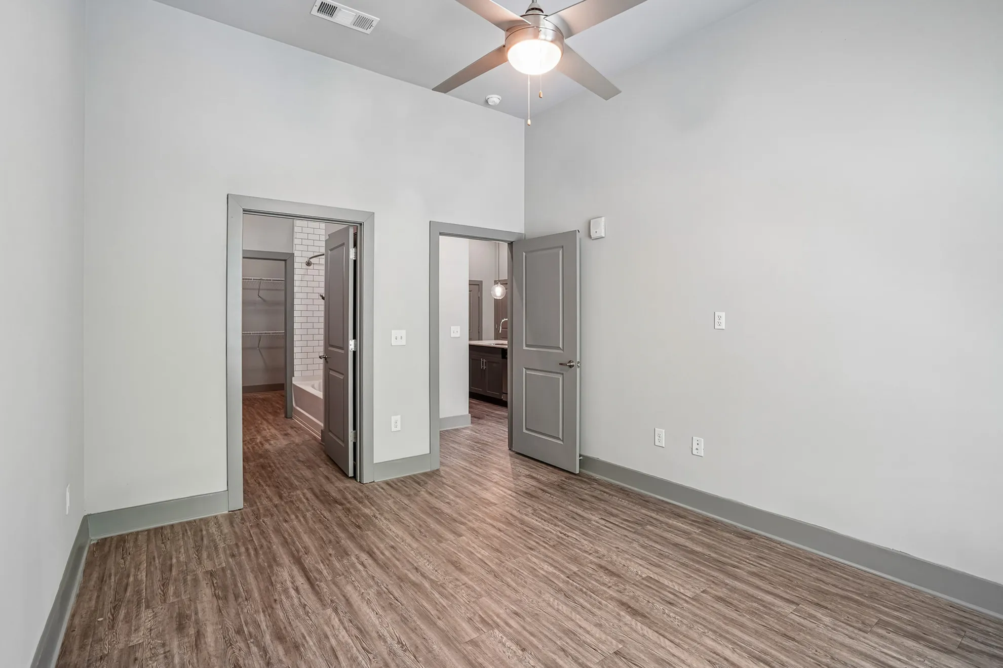 Spacious modern bedroom with elegant wood flooring, featuring an ensuite bathroom and walk-in closet.