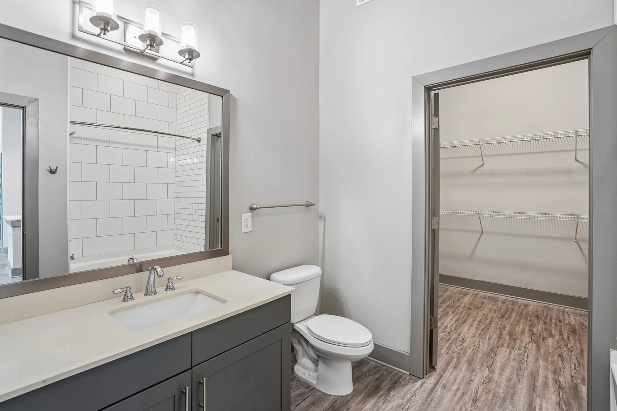 Modern bathroom with sleek fixtures, spacious vanity, and an attached walk-in closet with ample shelving space.