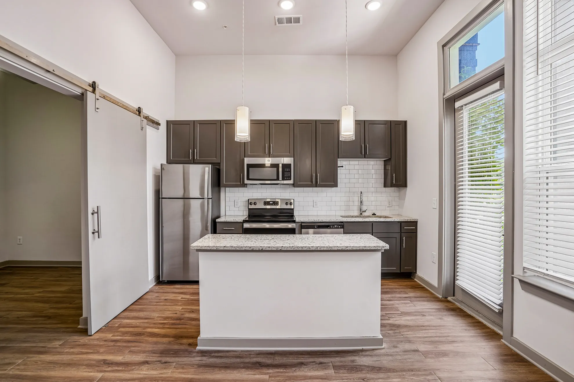 Modern kitchen with stainless steel appliances, granite countertops, and elegant cabinetry, featuring a stylish island and hardwood flooring.