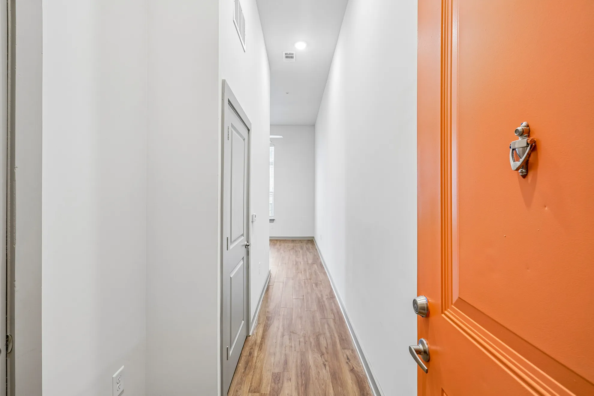 Bright and inviting hallway entrance with a striking orange door, setting the tone for a stylish and modern home.