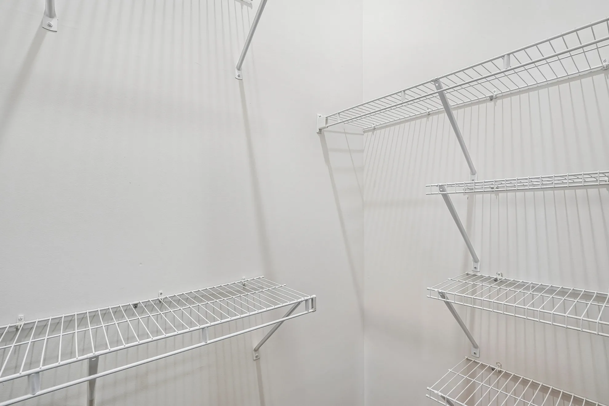 Bright and spacious walk-in closet with sturdy white wire shelving.