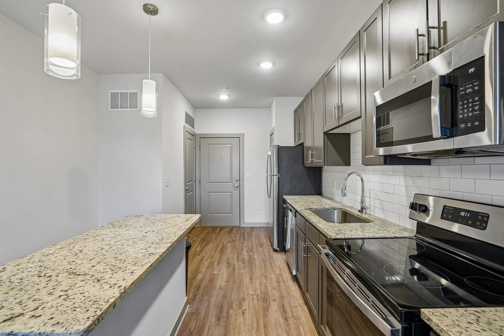 Modern kitchen with sleek granite countertops, stainless steel appliances, and elegant pendant lighting.