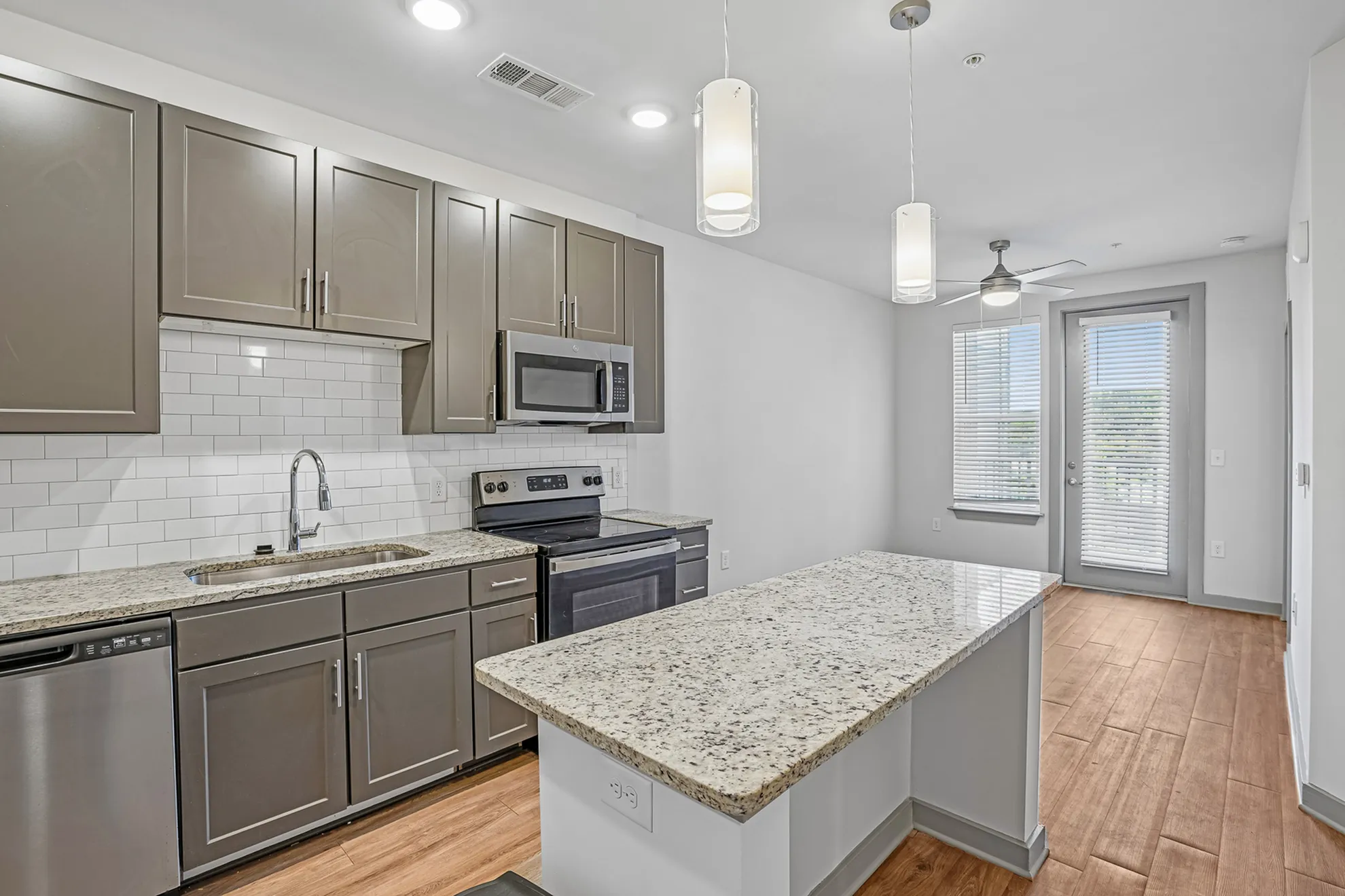 Modern kitchen with elegant granite countertops, stainless steel appliances, and stylish pendant lighting, highlighting a spacious and inviting atmosphere.