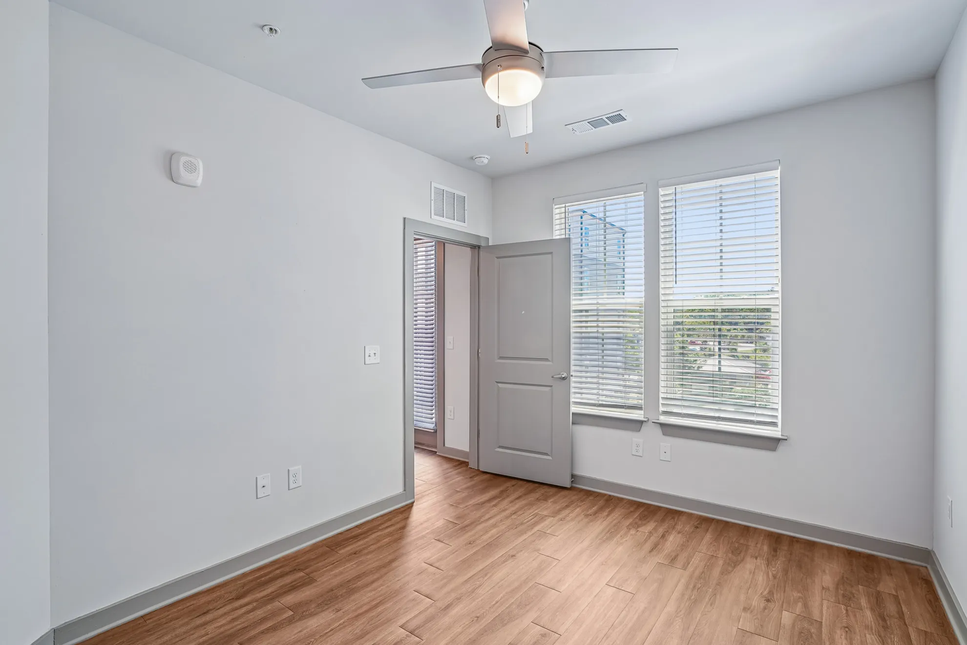 Bright, cozy room with elegant wooden flooring and large windows inviting natural light.