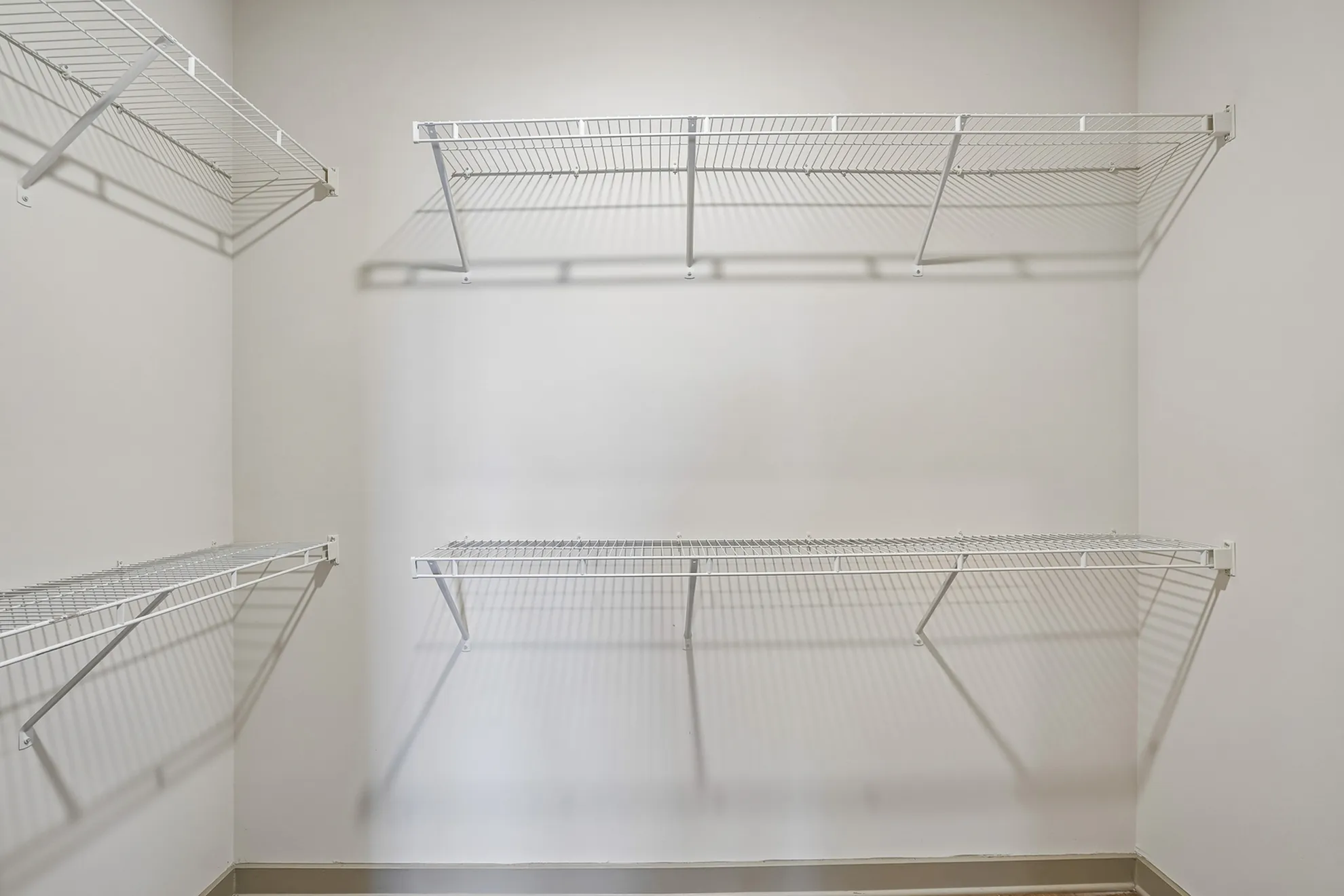 Spacious walk-in closet with clean white shelves ideal for organized storage.