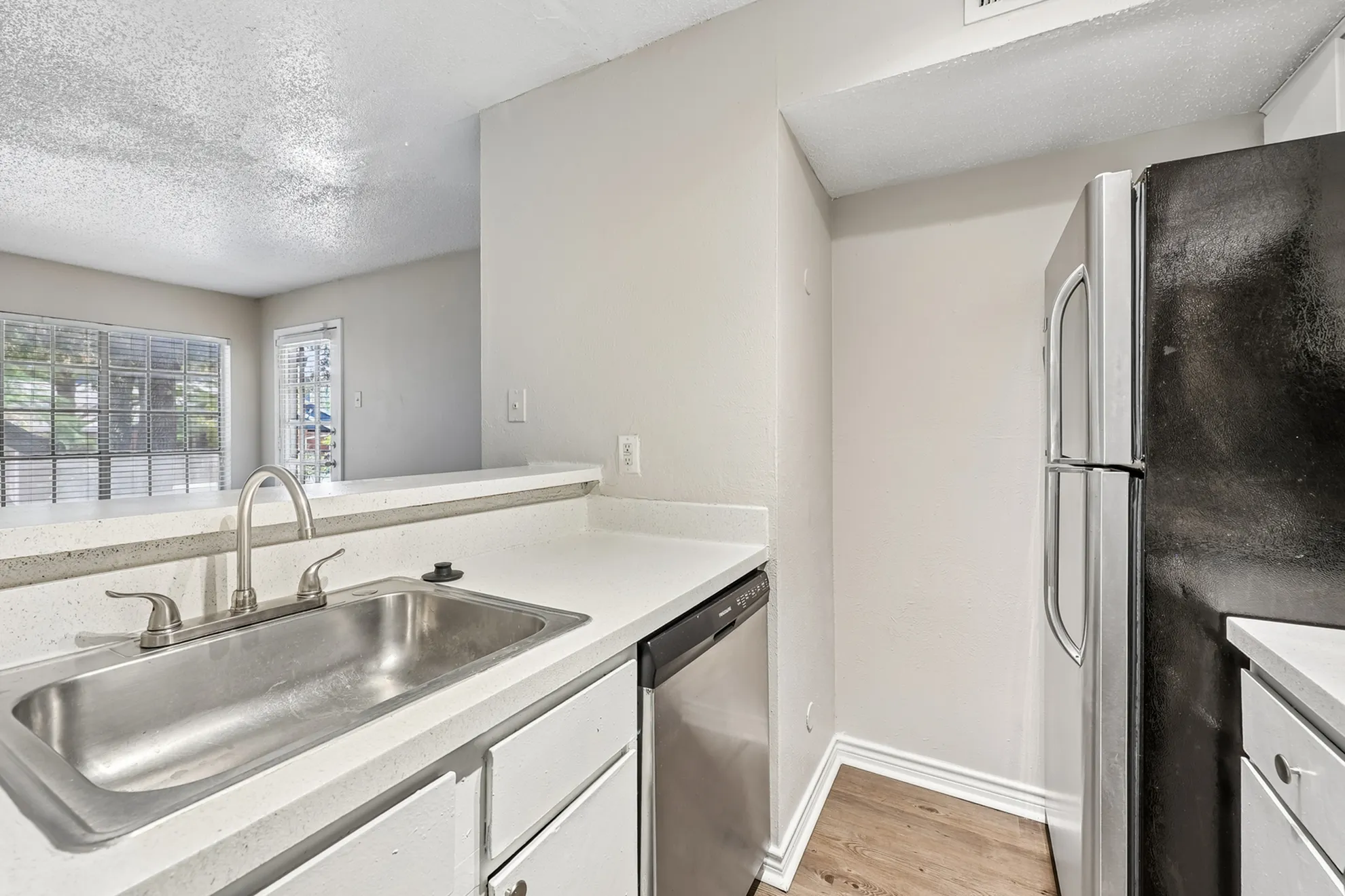 Modern kitchen with sleek countertops, stainless steel appliances, and a spacious sink, offering bright natural light through large windows.
