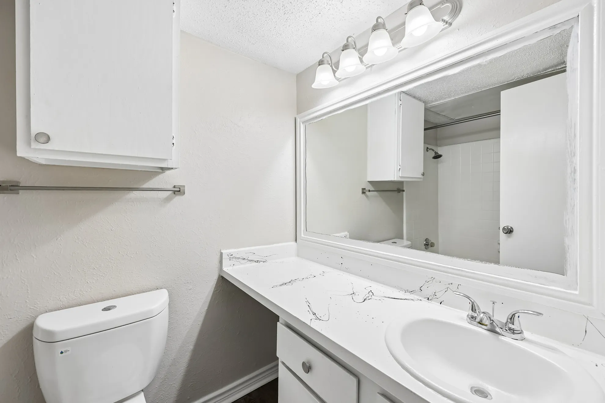 Elegant bathroom featuring a modern vanity with a large mirror, stylish lighting, and immaculate white fixtures.