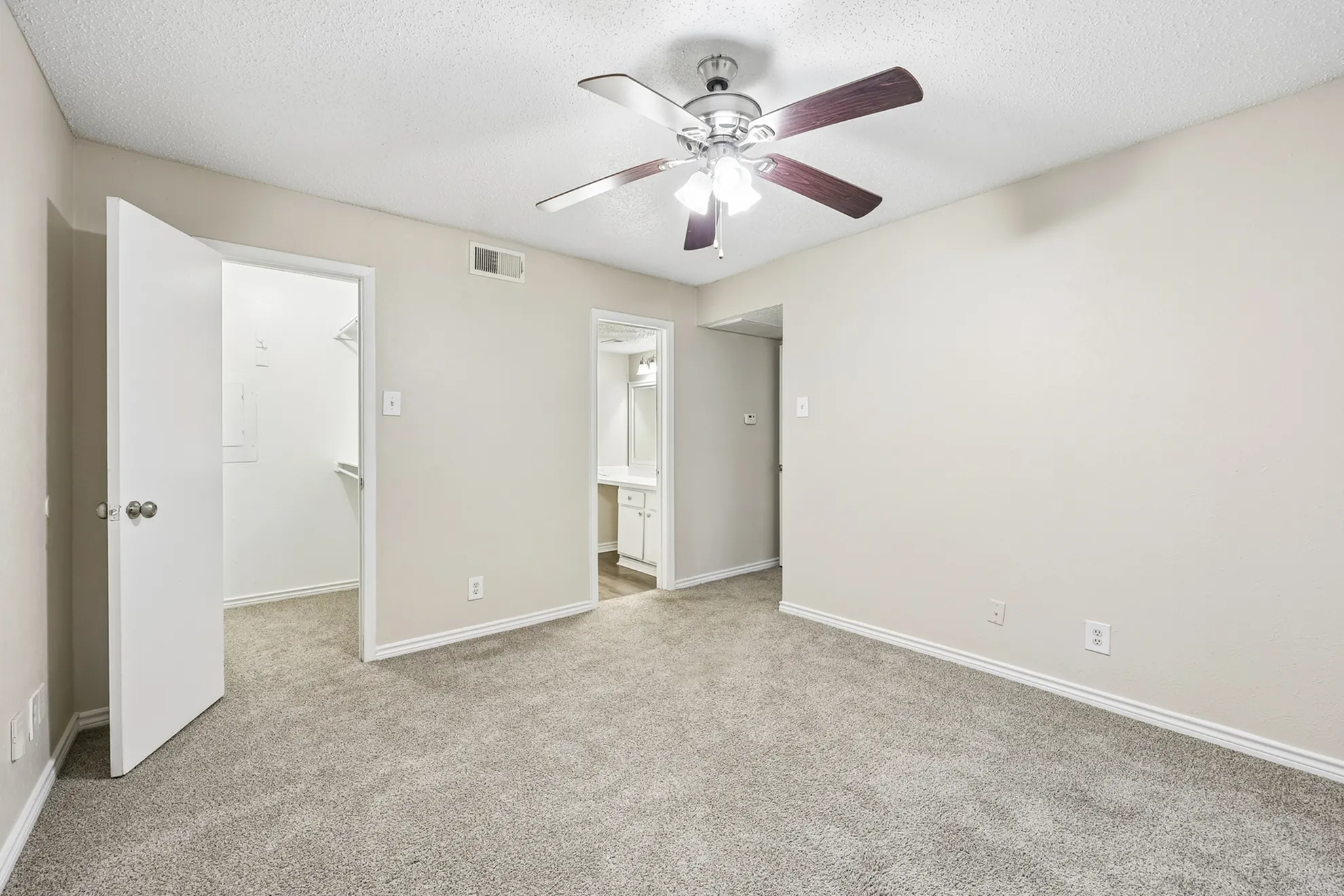Bright bedroom featuring plush carpet, a ceiling fan, and an attached walk-in closet.