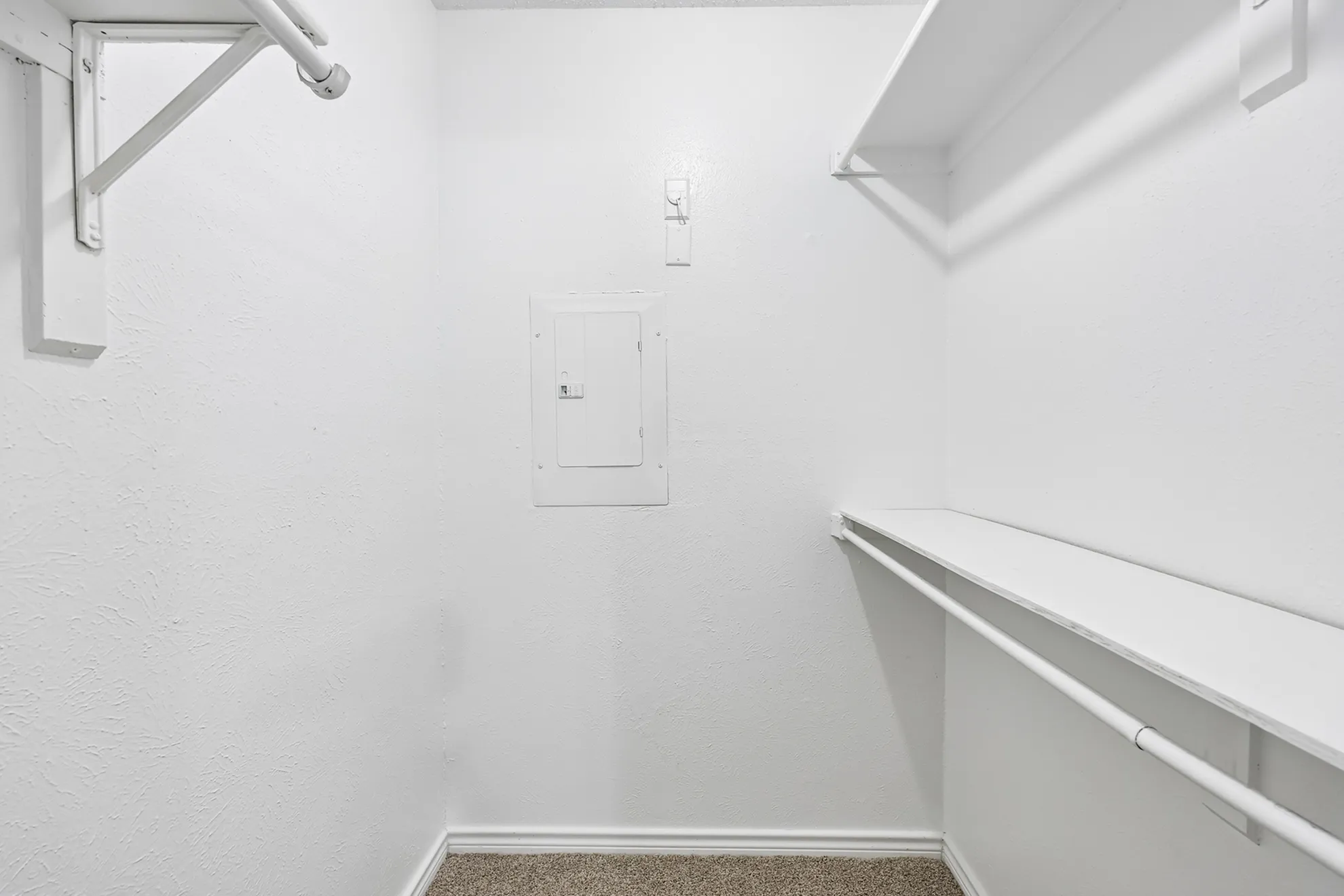Spacious walk-in closet with built-in shelving and hanging rod, perfect for organized storage.