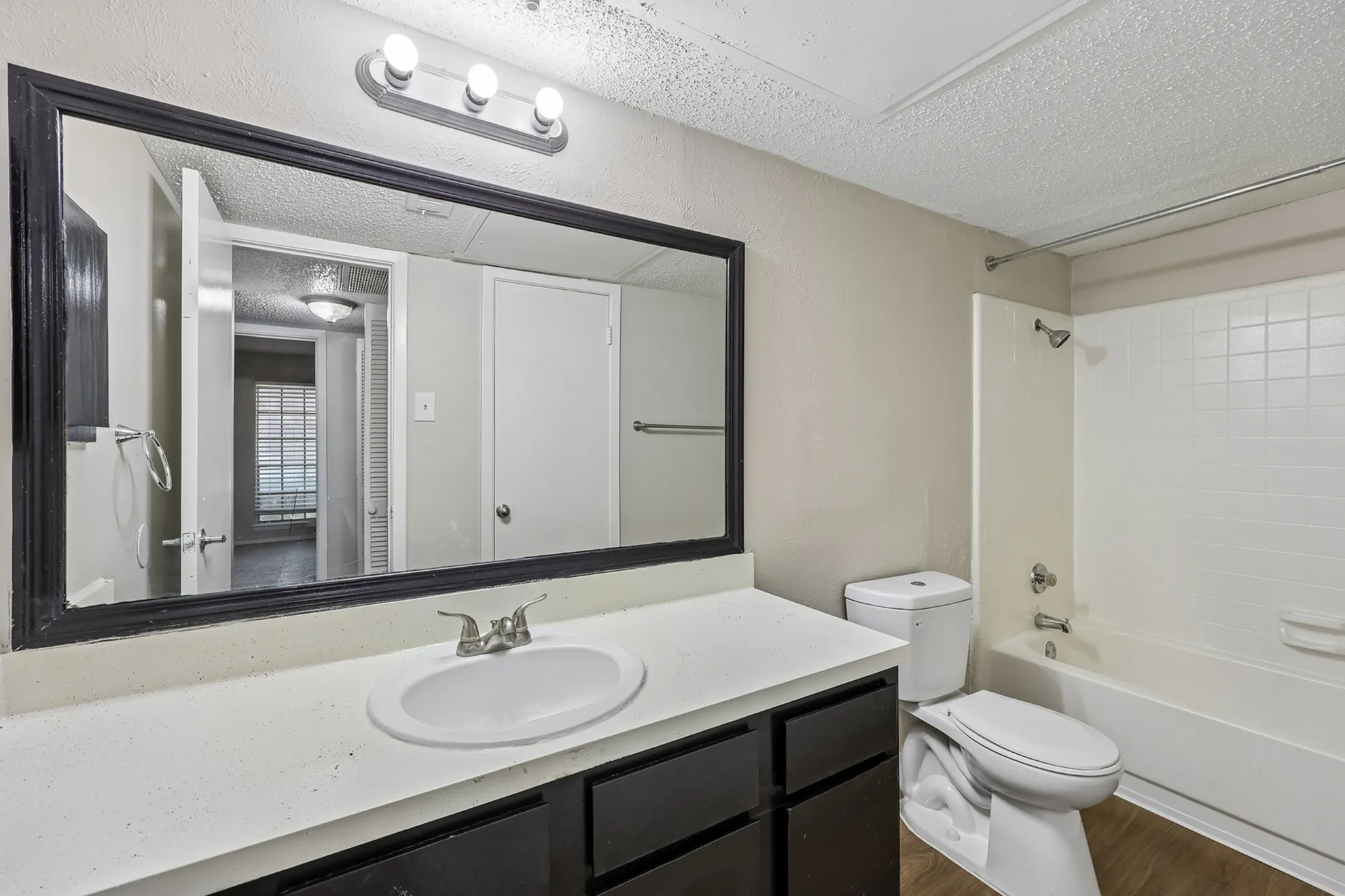 Modern bathroom with sleek countertop, large mirror, and inviting bathtub in a stylish apartment.