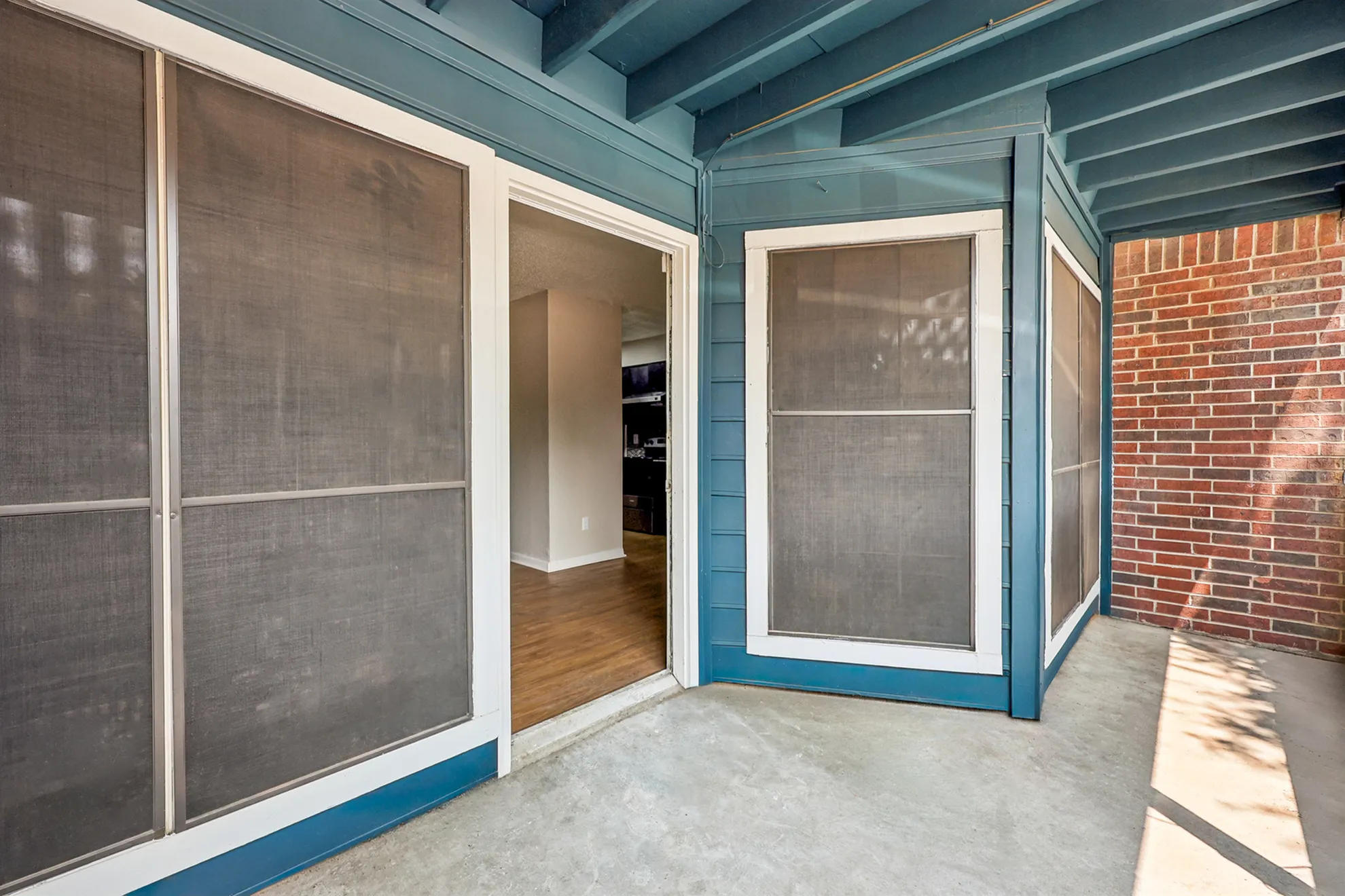 Charming outdoor entrance with a modern blue facade and inviting indoor view, perfect for enjoying sunny days.