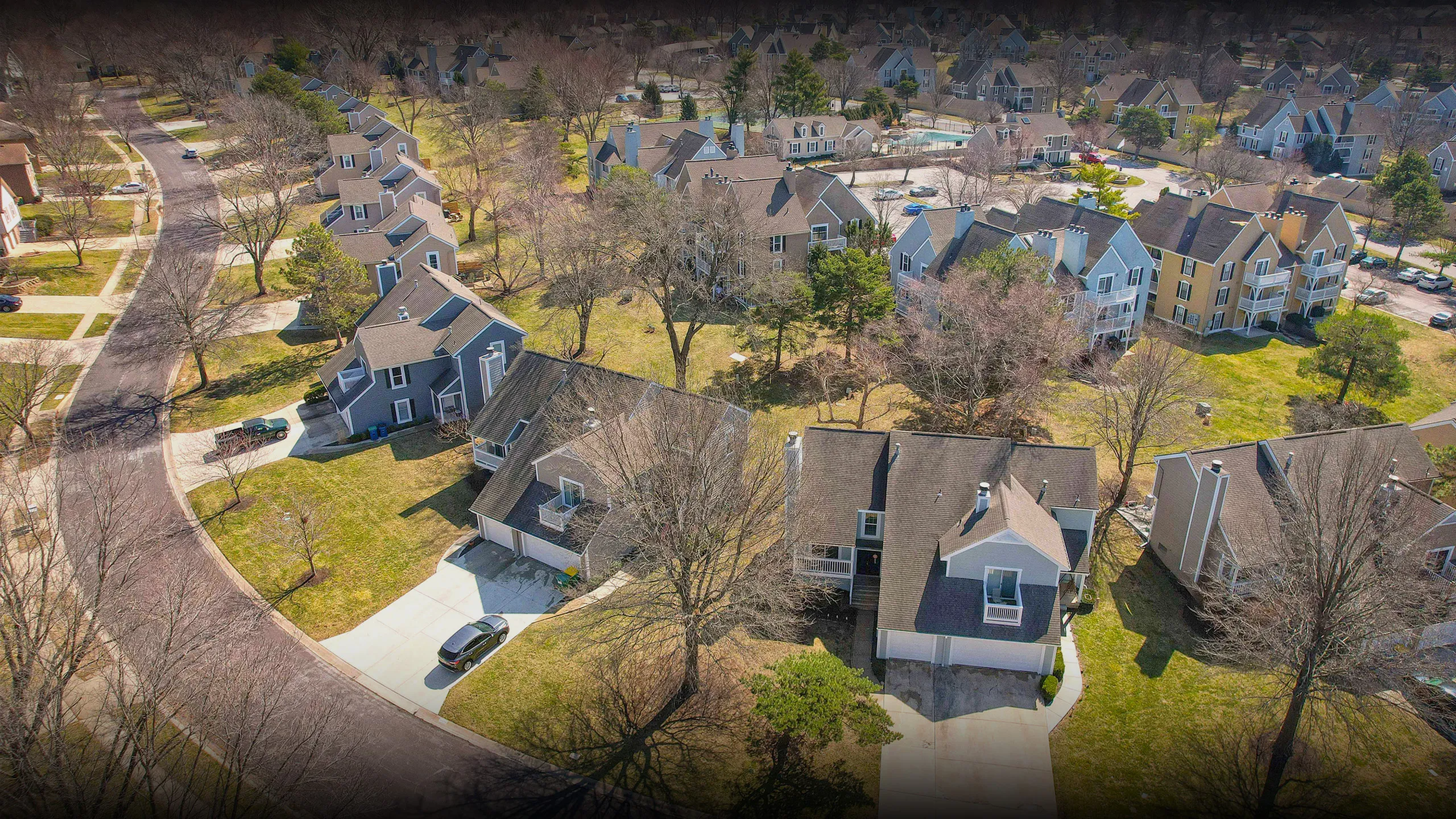 Charming suburban neighborhood with stylish homes, lush green lawns, and tree-lined streets basking in natural sunlight.