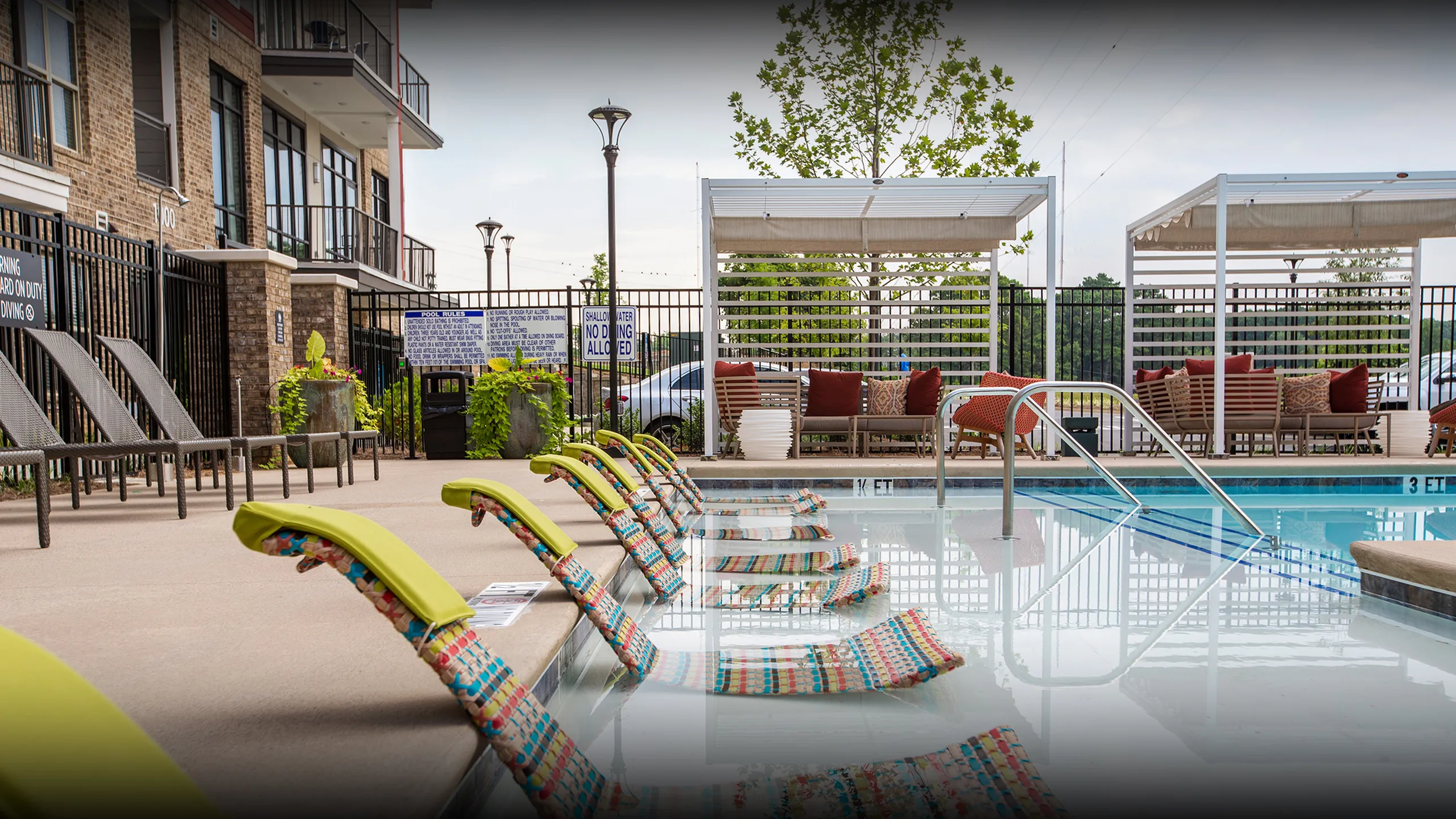 Inviting apartment pool area featuring stylish lounge chairs and shaded seating for ultimate relaxation.