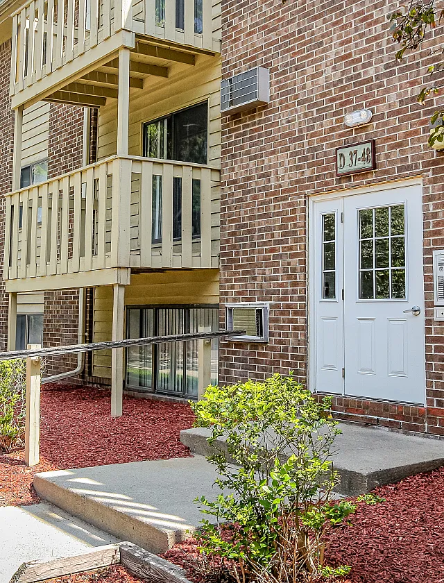 Inviting brick exterior of apartment building with charming balconies and lush landscaping for an upscale urban living experience.