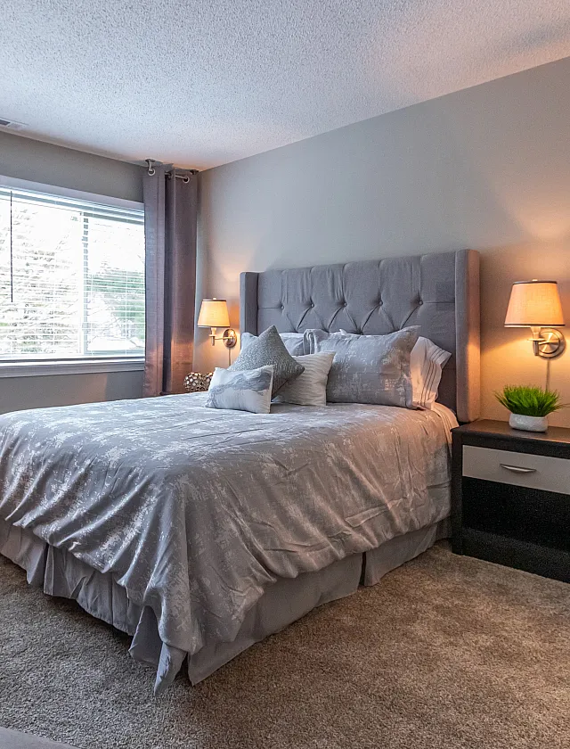 Inviting bedroom with elegant decor, plush bedding, and ample natural light from large windows.