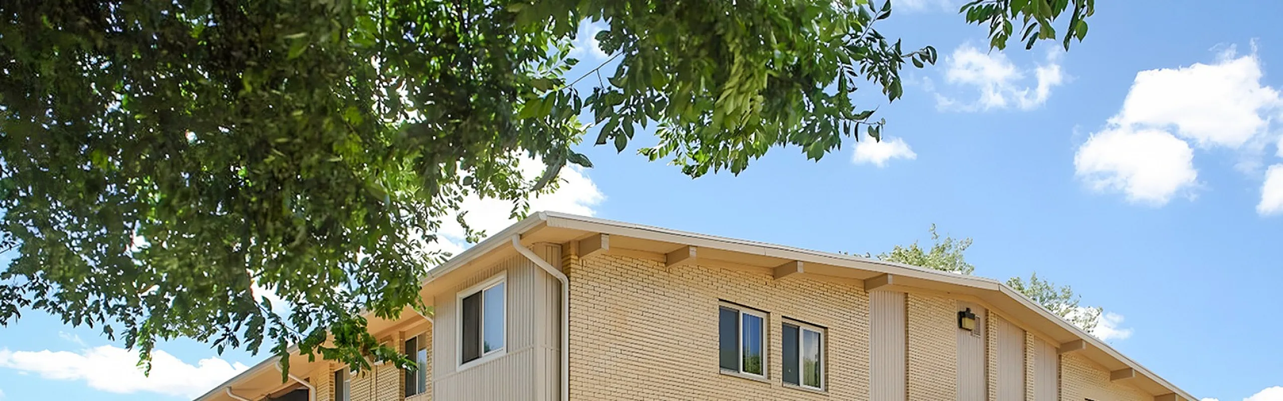 Charming and inviting apartment building surrounded by lush greenery, with bright windows and a well-maintained exterior, perfect for modern living.
