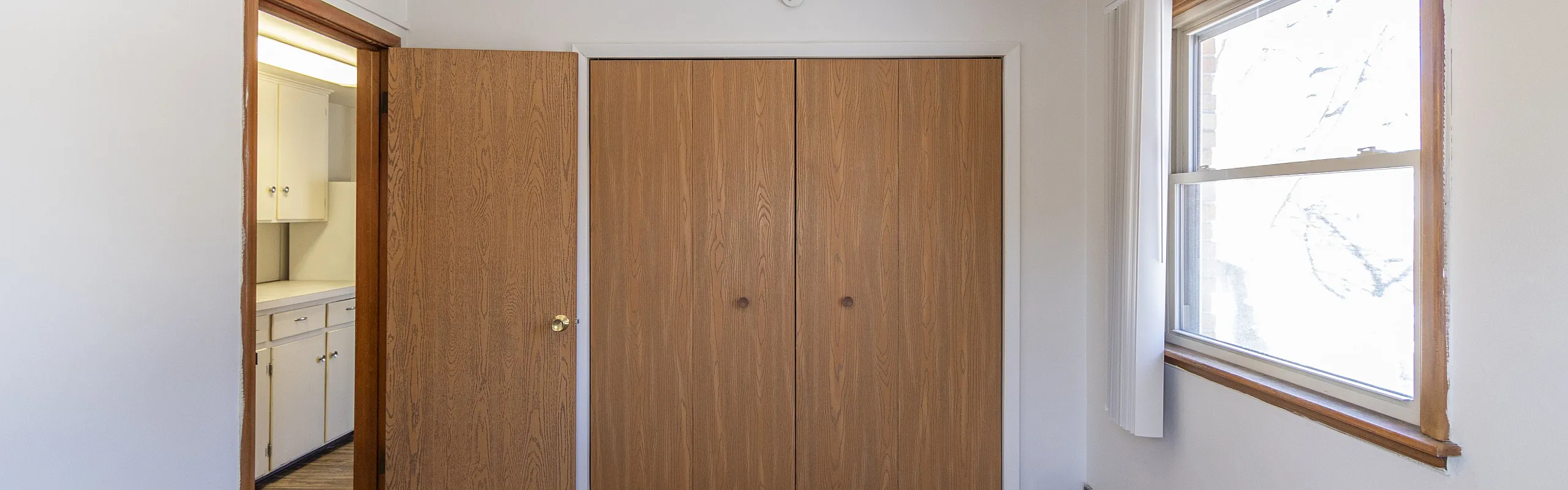 Bright bedroom with plush carpet, ample closet space, and natural light from a large window.