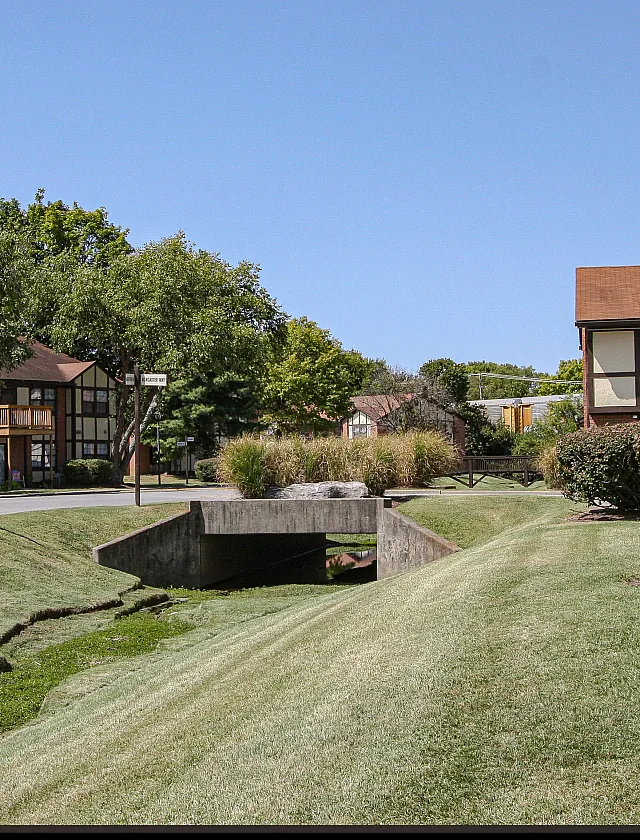 Charming residential area with lush green lawns, elegant townhouse architecture, and serene landscaping under a clear blue sky.