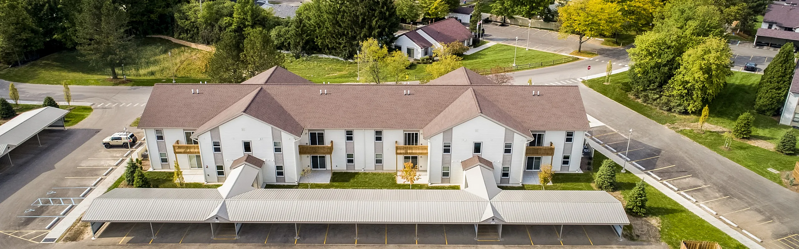 Charming apartment complex surrounded by lush greenery with ample parking and modern architecture.