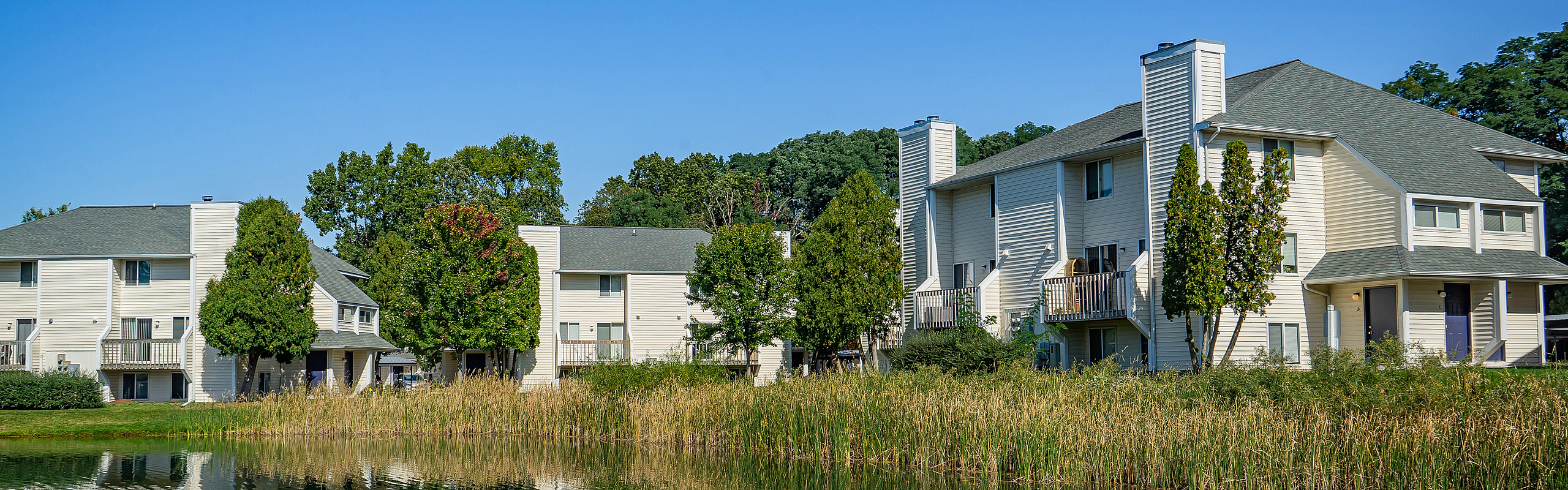 Charming lakeside apartments with modern architecture surrounded by lush greenery and tranquil waters.