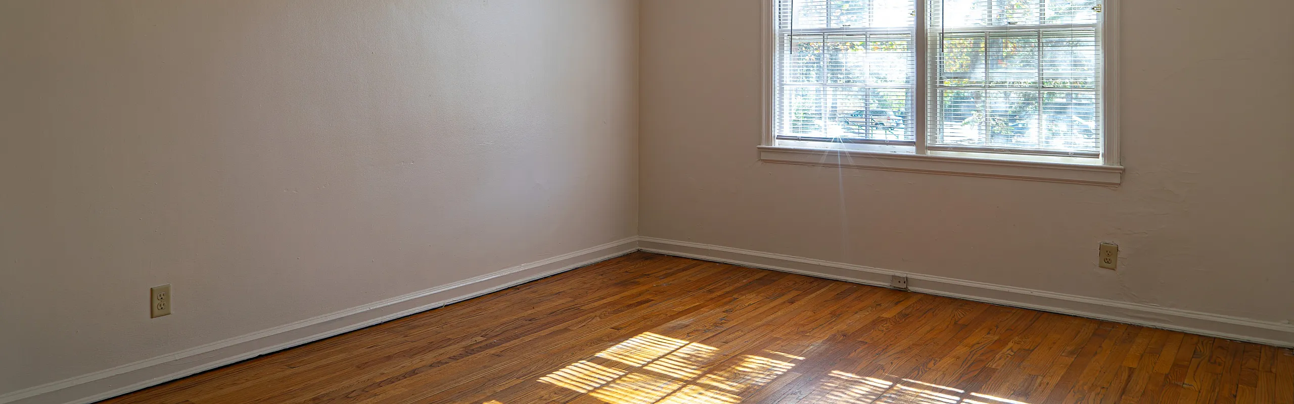 Bright, inviting room with polished hardwood floors and a large window allowing abundant natural light.