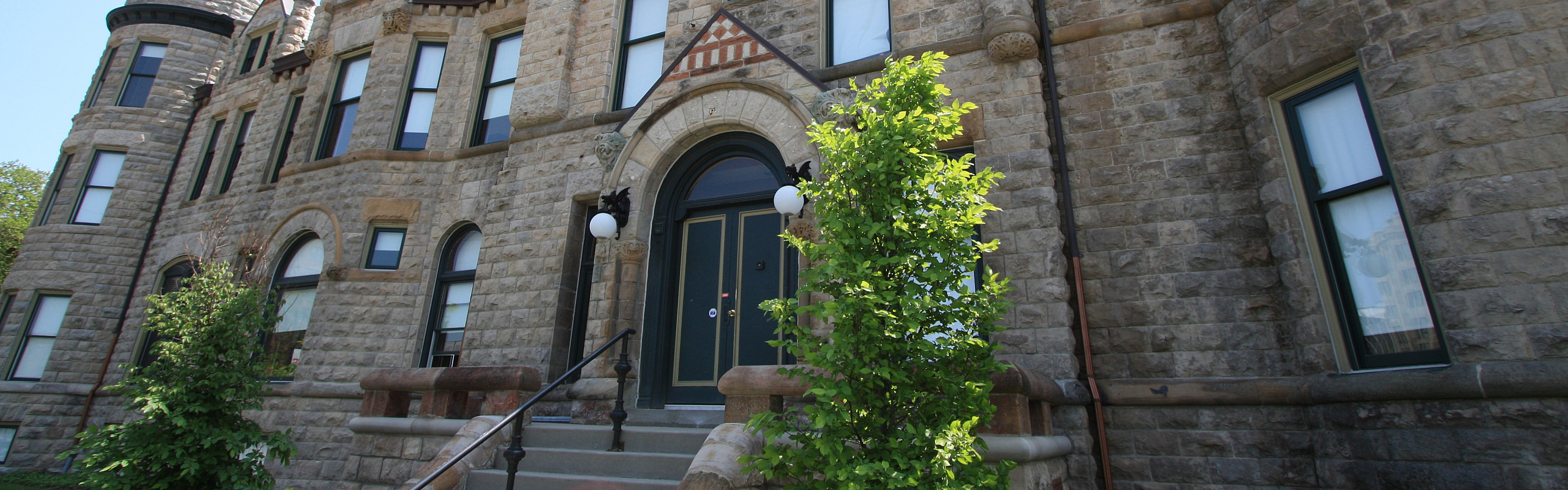 Charming stone-front historical building with elegant architecture and lush landscaping, exuding timeless luxury and character.