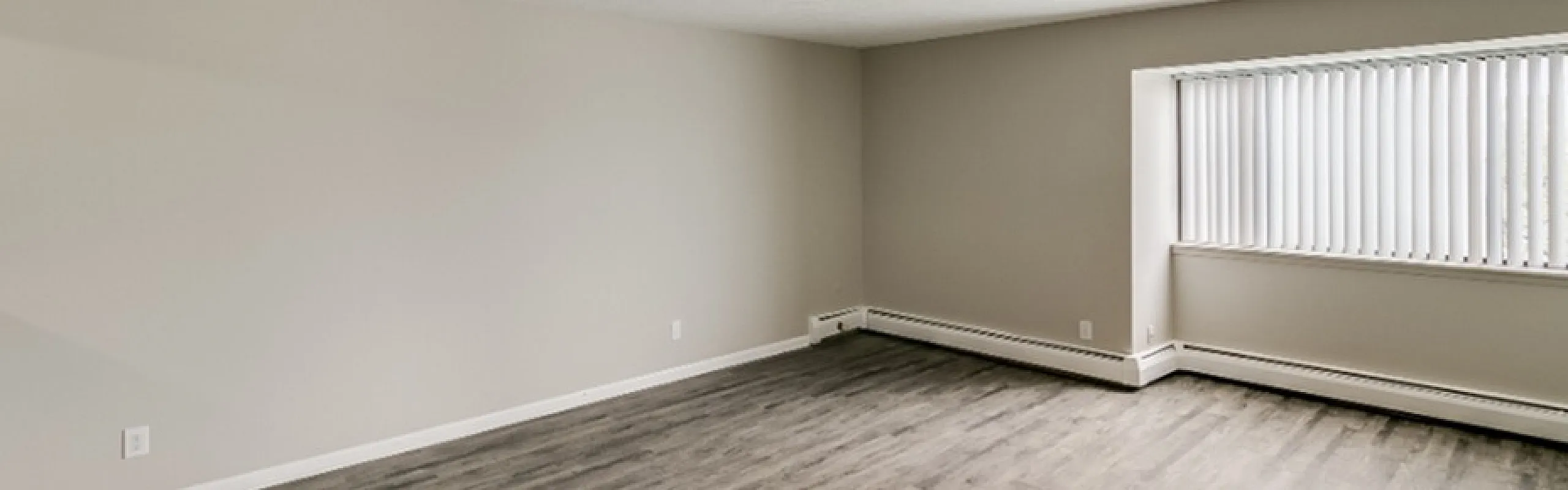 Spacious, light-filled living area with chic flooring and large window, perfect for modern living.