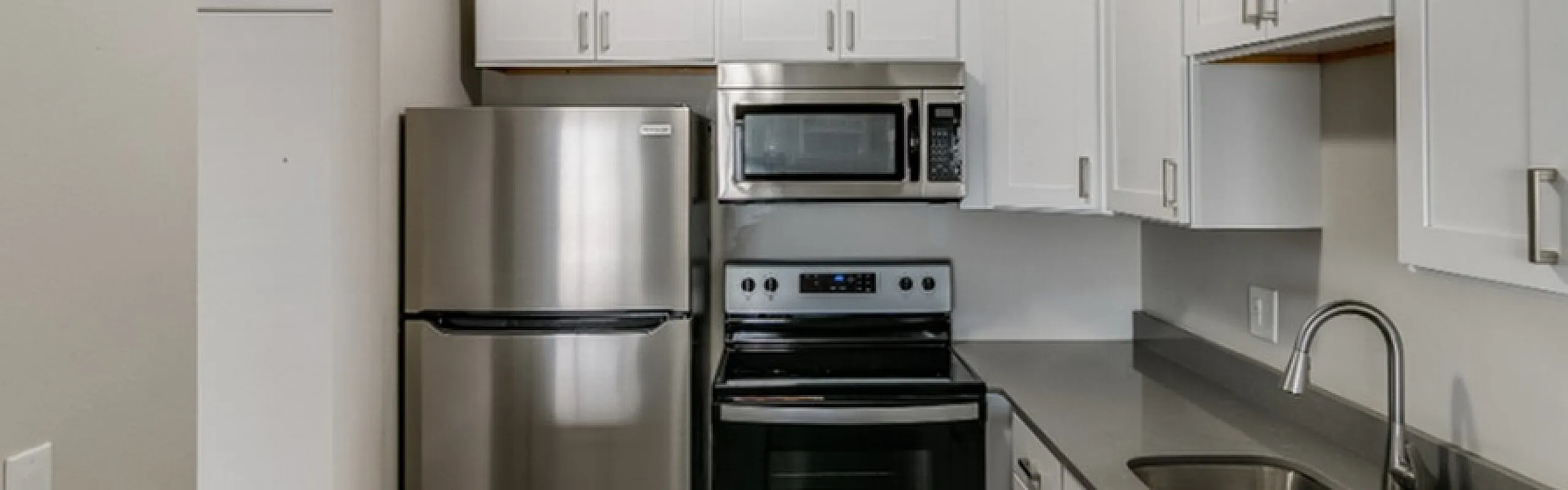 Modern kitchen with sleek stainless steel appliances, elegant white cabinets, and spacious countertops.