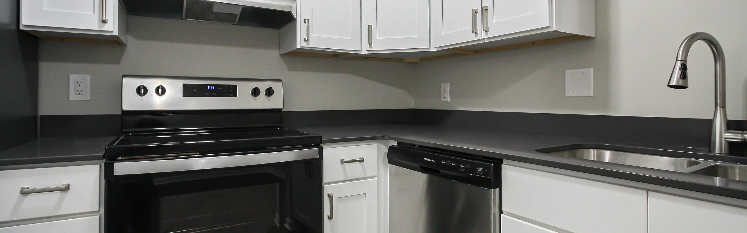 Modern kitchen with sleek stainless steel appliances, elegant white cabinetry, and dark countertops.