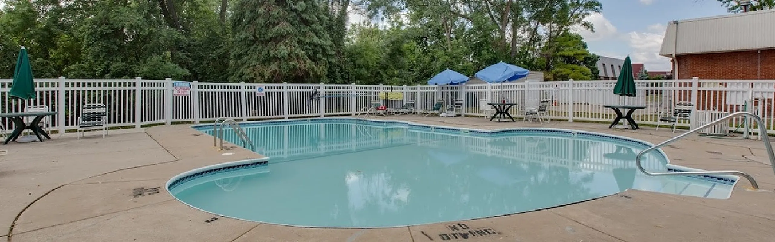 Inviting outdoor pool area with lush greenery and convenient seating options, perfect for relaxing and enjoying sunny days.