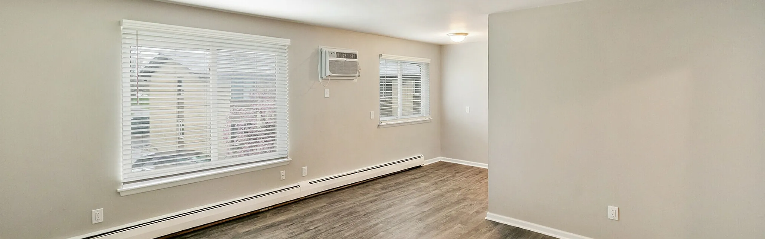 Bright and spacious living area with sleek wooden flooring and large windows for abundant natural light.