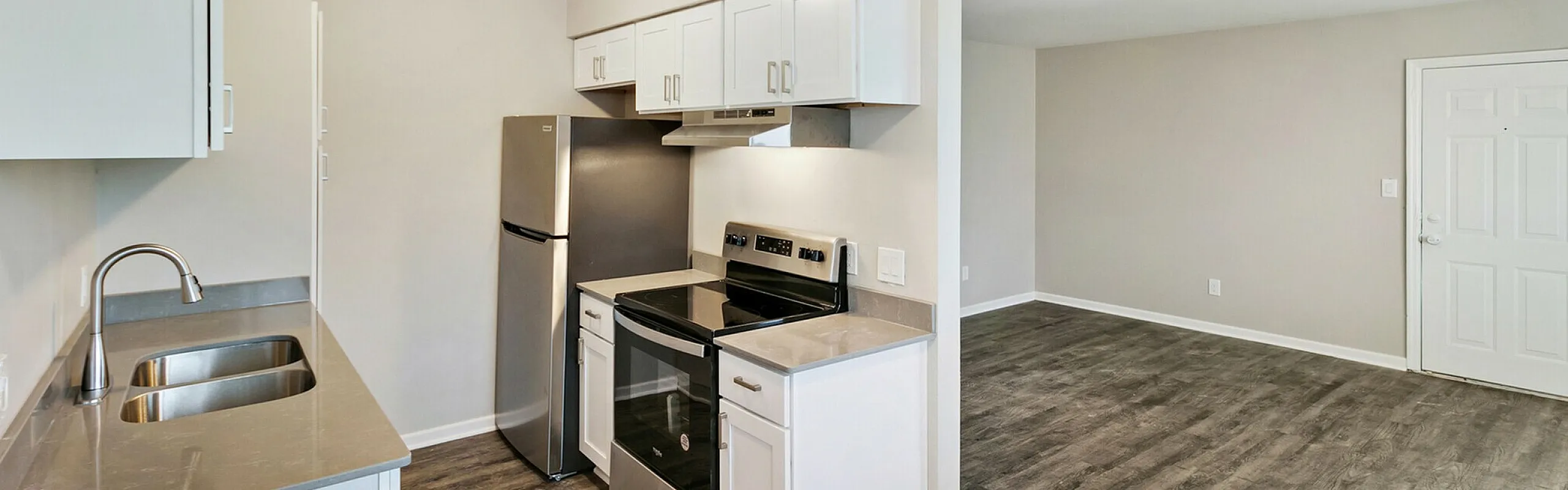 Modern open-plan kitchen with sleek stainless steel appliances and elegant hardwood floors.