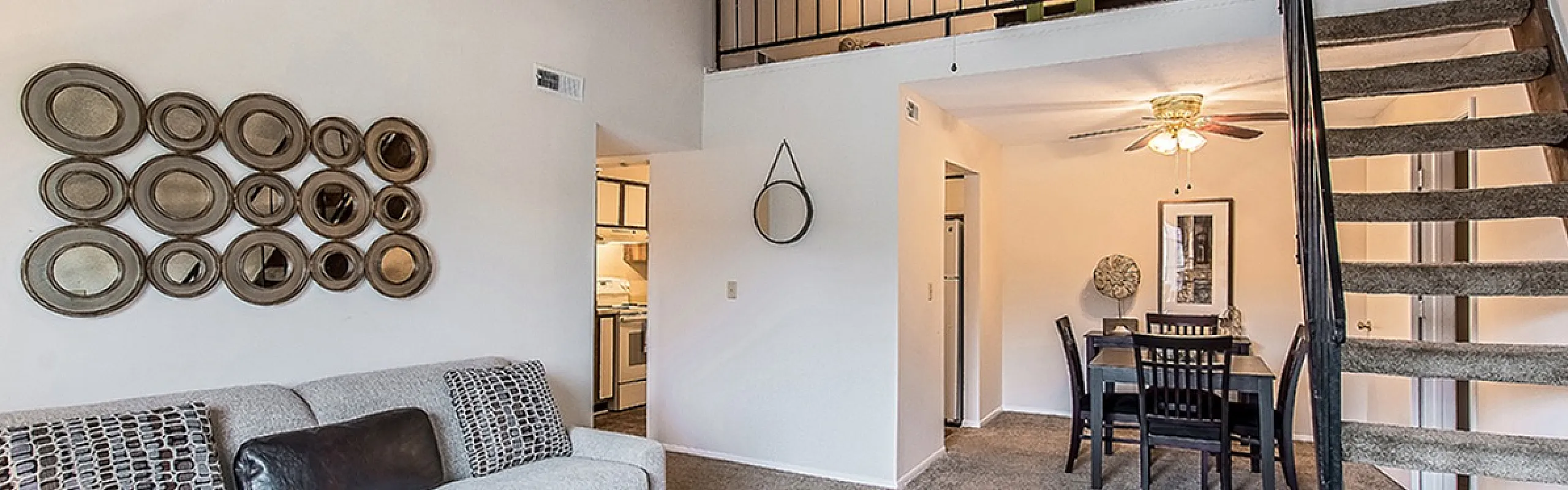 Stylish apartment interior with a cozy open-plan living area, featuring a plush sofa, elegant wall decor, a sleek coffee table, and a modern spiral staircase leading to an upper level.