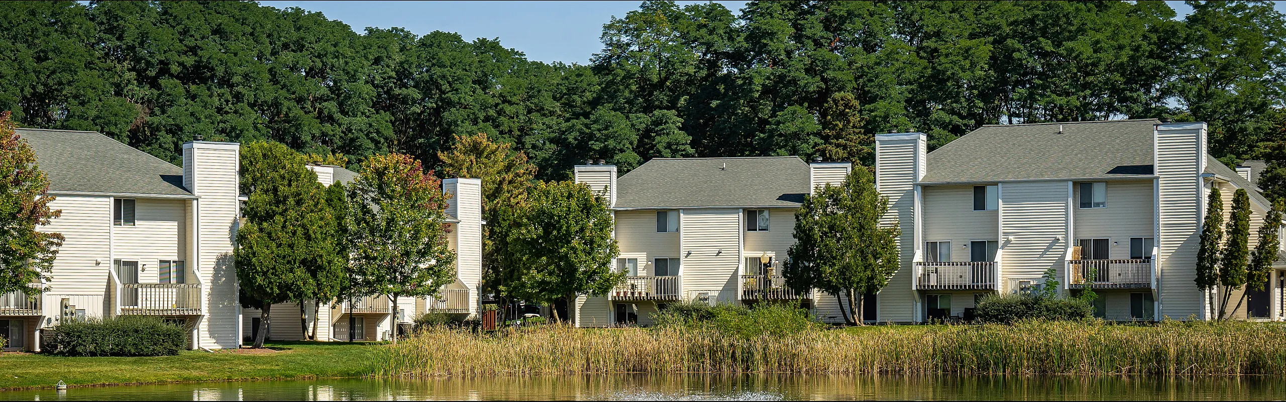 Charming apartment homes nestled amid lush greenery, offering serene pond views and inviting outdoor balconies.