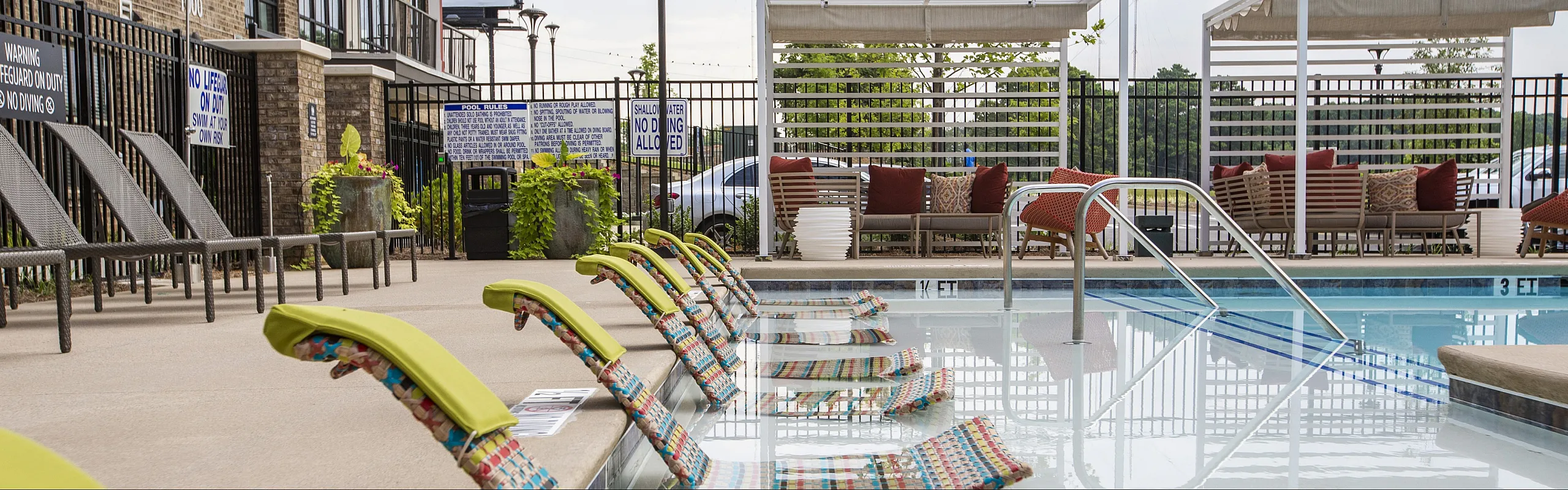 Inviting poolside area featuring vibrant loungers, cozy seating with plush cushions, and lush greenery for a relaxing oasis.