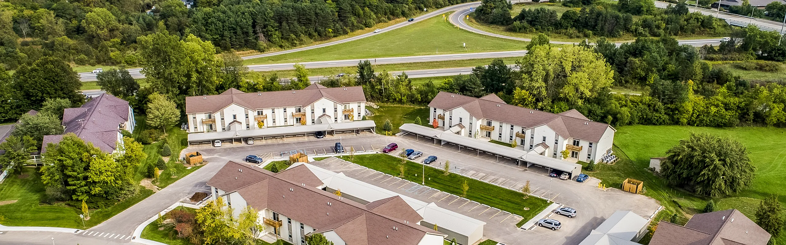 Charming suburban apartment complex surrounded by lush greenery, offering serene living just off the highway.