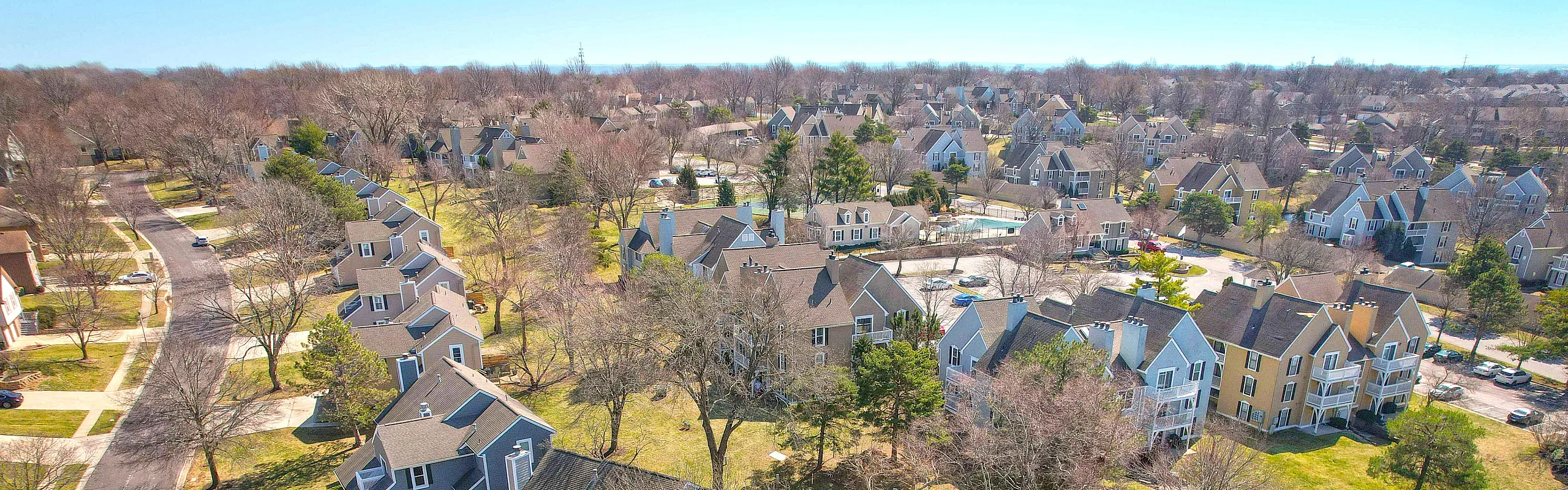 Vibrant aerial view of a picturesque suburban neighborhood showcasing charming houses nestled among lush trees and open green spaces.