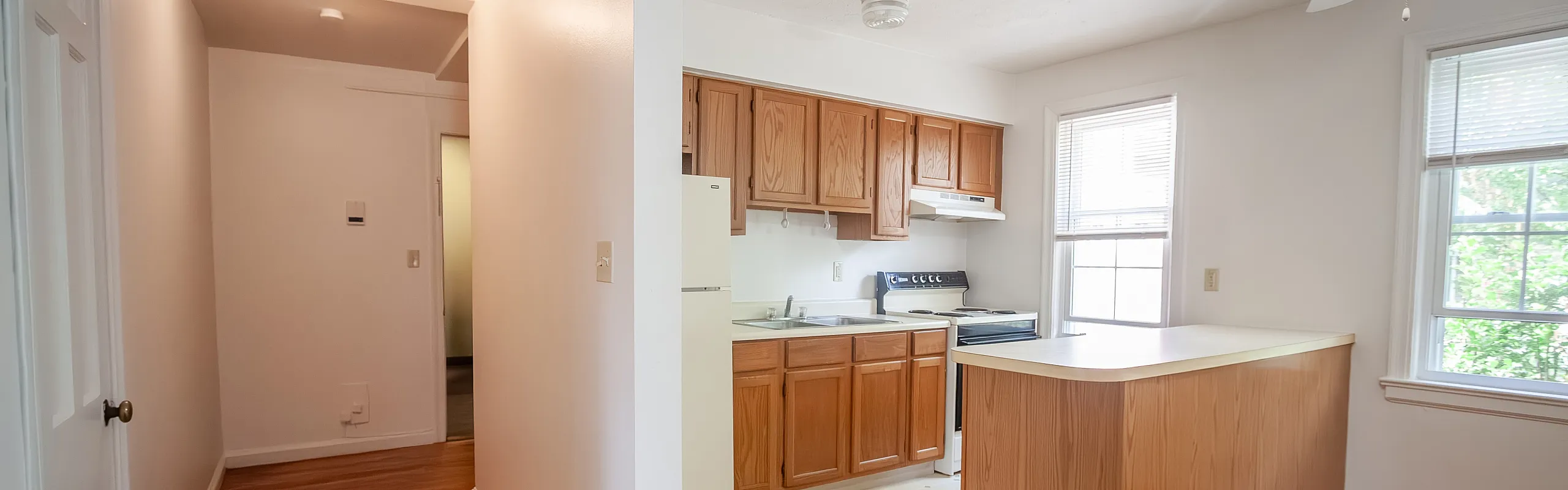 Bright kitchen with wooden cabinets and large windows offering natural light.