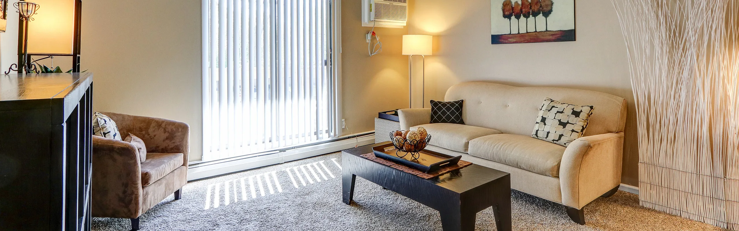 Cozy and inviting living room with plush beige sofa, stylish accent chairs, modern black coffee table, and soft lighting creating a warm ambiance.