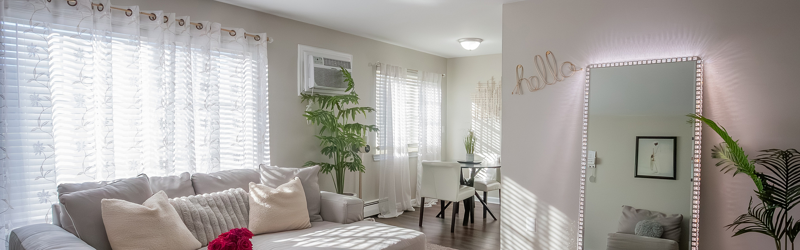 Bright and inviting living room with stylish decor, cozy seating, lush indoor plants, and natural light streaming through sheer curtains.