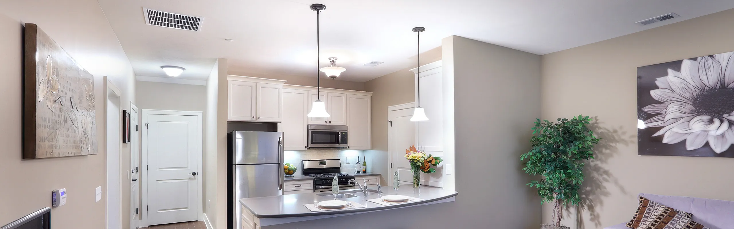 Elegant open-plan kitchen with modern stainless steel appliances, stylish pendant lighting, and fresh floral accents, offering a harmonious blend of functionality and design.