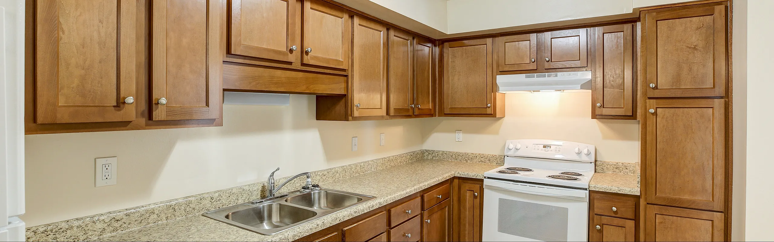 Inviting kitchen with warm wooden cabinets, sleek countertops, and modern appliances adding charm and functionality.