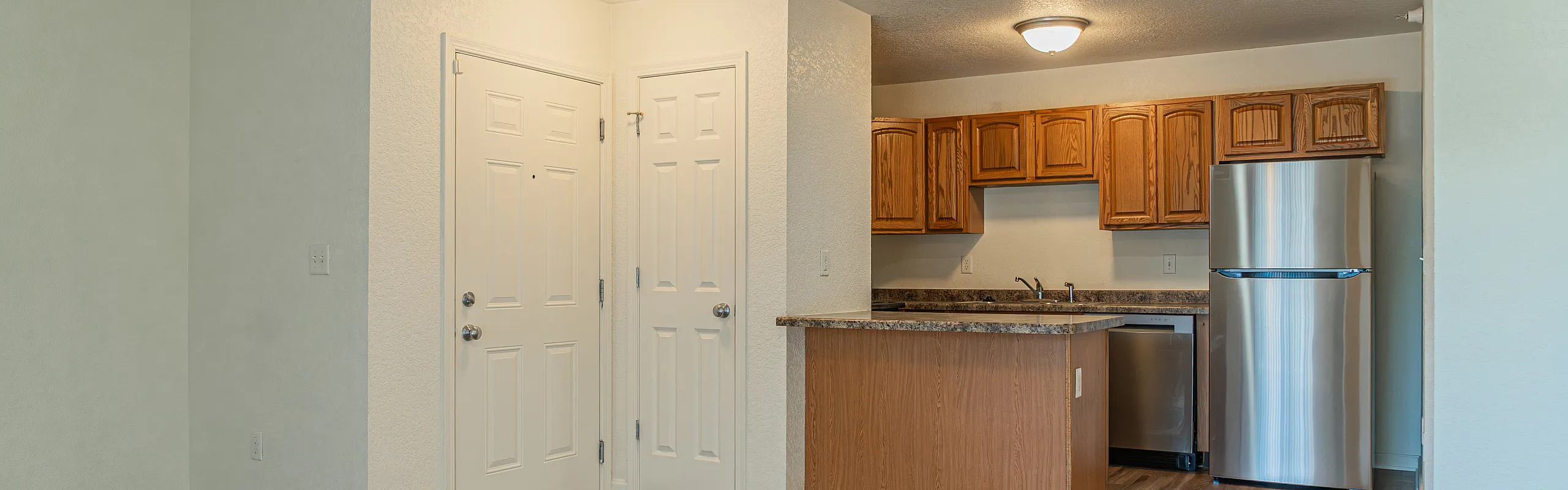 Modern kitchen area with sleek stainless steel appliances, warm wooden cabinetry, and elegant granite countertops, perfect for culinary enthusiasts.