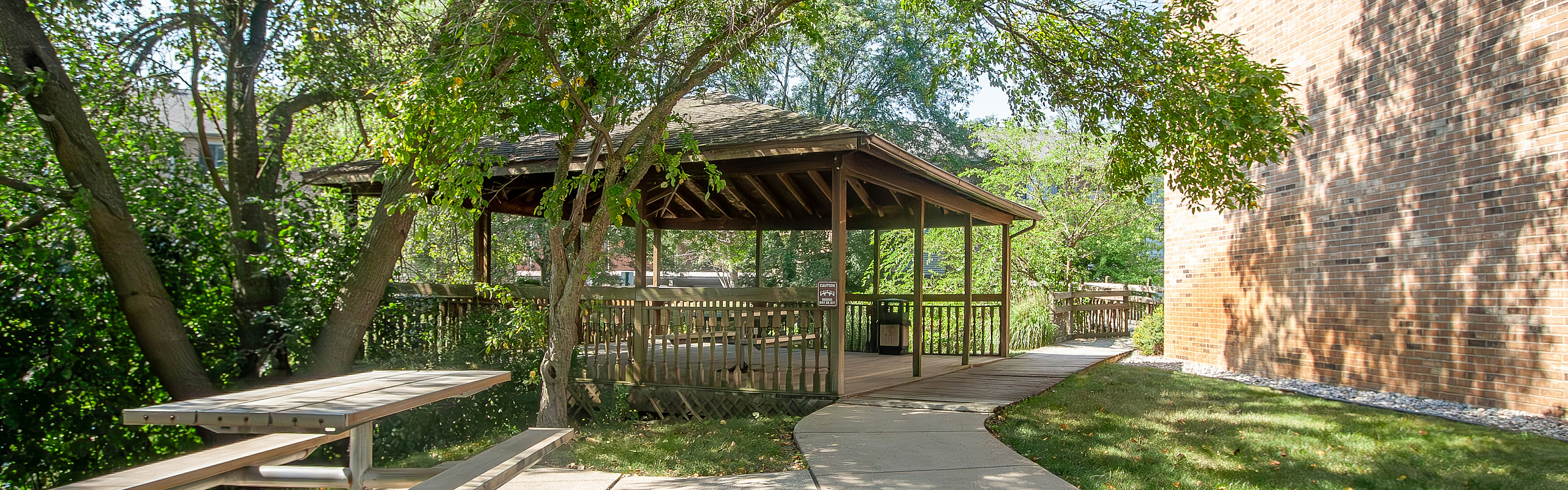 Charming wooden gazebo nestled in a lush garden setting with a cozy picnic area, perfect for relaxation and outdoor gatherings.