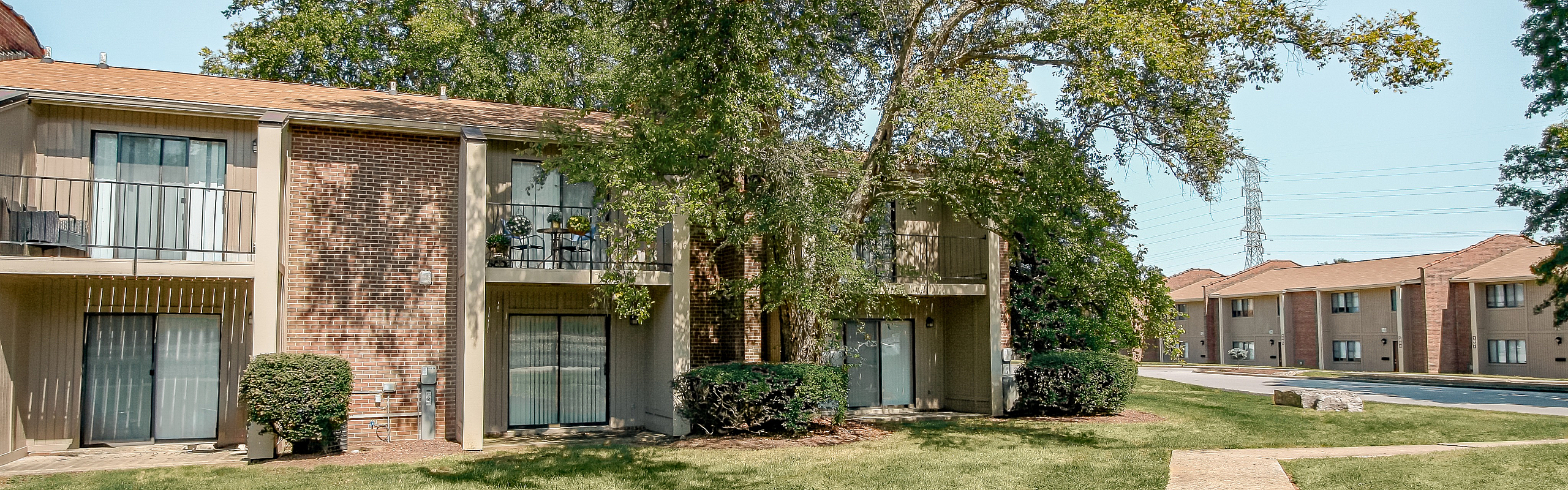Charming apartment building with private balconies, surrounded by lush greenery and bathed in natural sunlight.