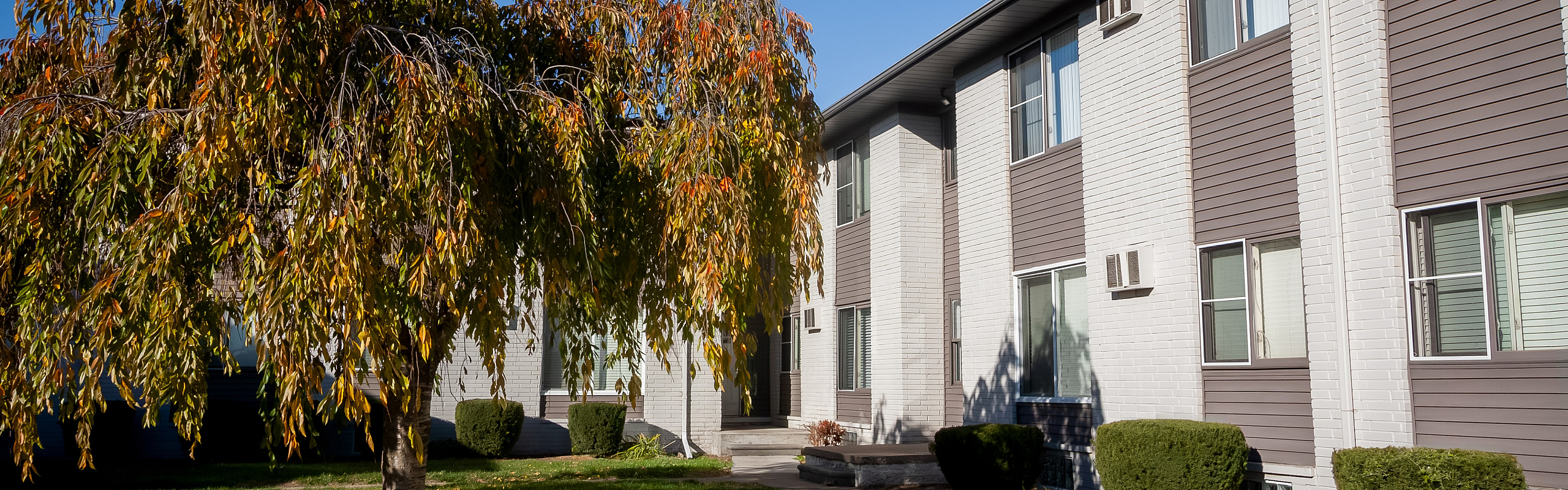 Charming apartment complex exterior with lush greenery and inviting autumn colors.