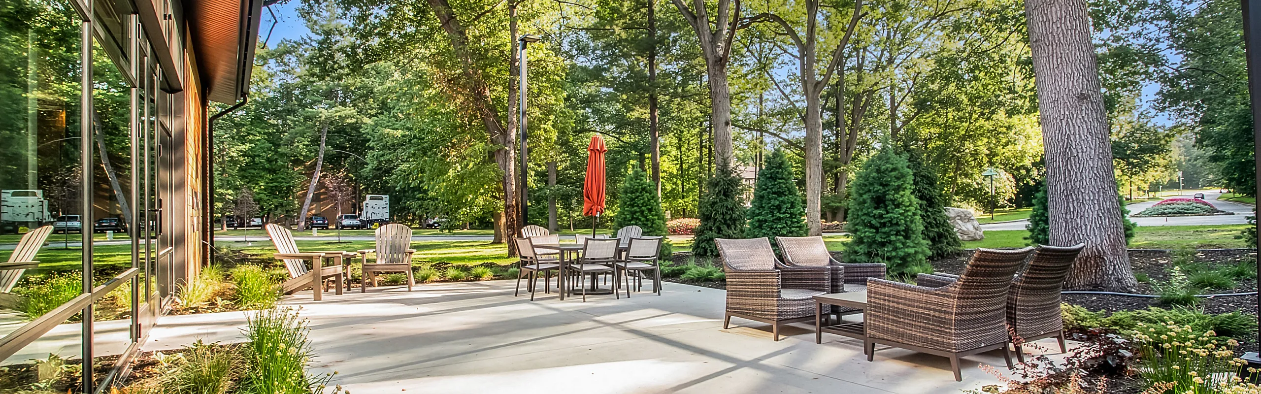 Inviting outdoor patio with modern rattan furniture, surrounded by lush green trees and a serene garden setting.
