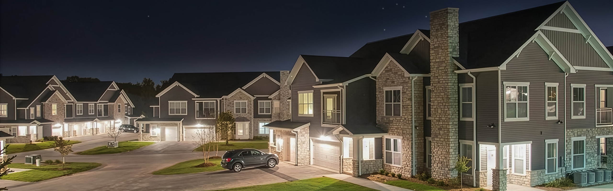 Charming nighttime view of a modern townhouse community with well-lit exteriors and elegant architecture.